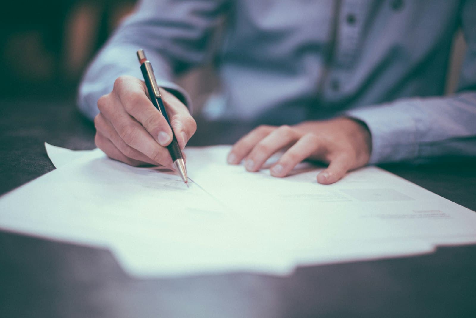 An accountant working through paperwork with a fountain pen at a desk