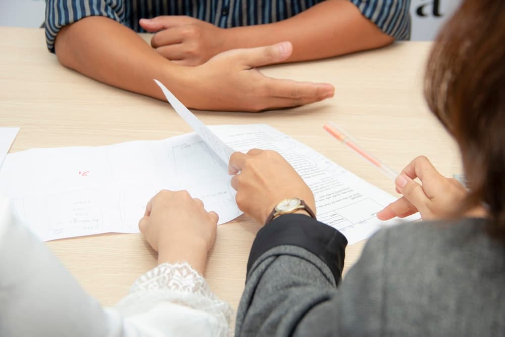 Two people reviewing documents across a meeting table