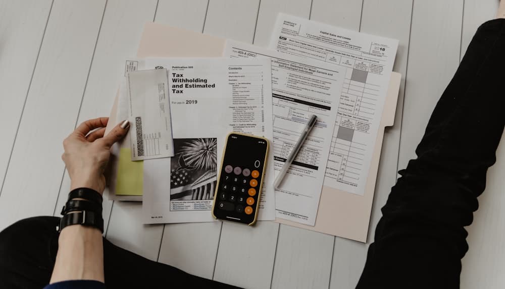 Hands checking figures on paper beside a pen and calculator