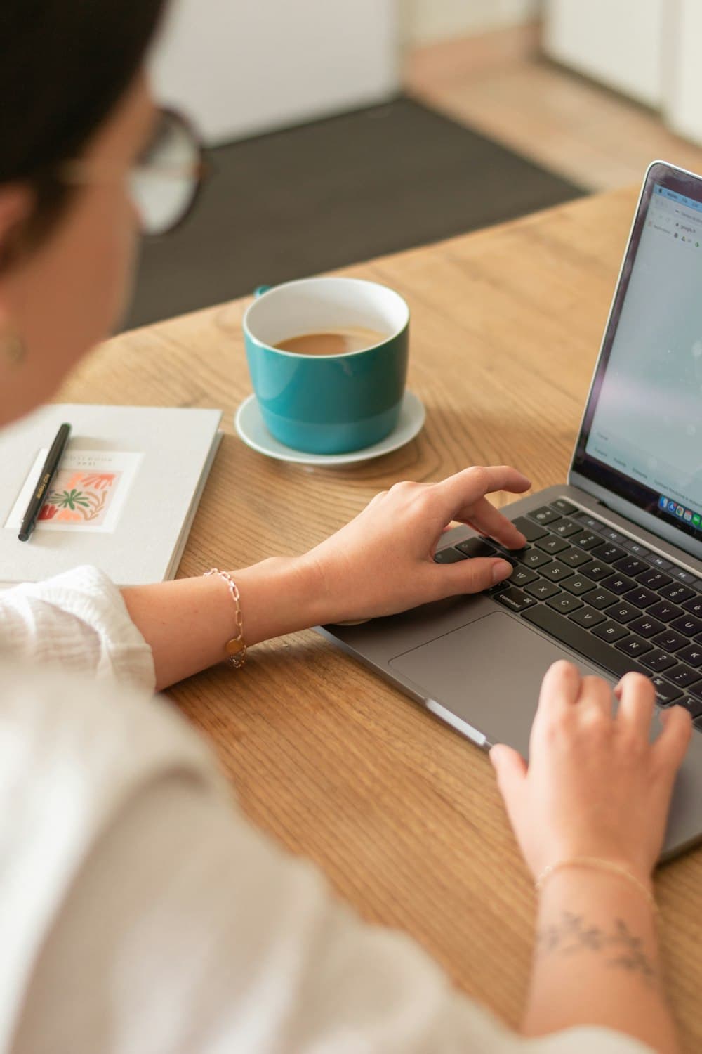 A person working on a laptop at a wooden table