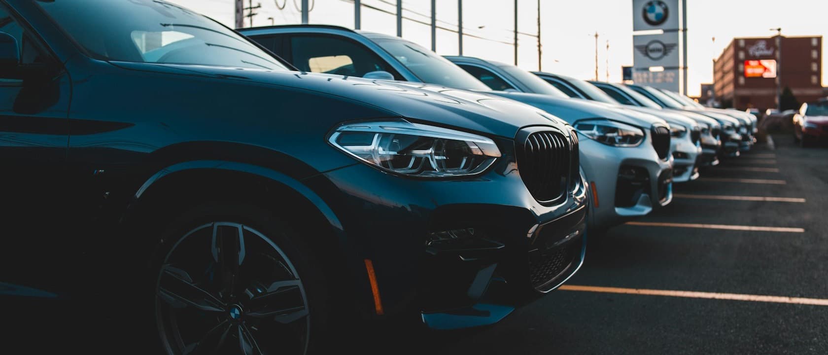 A row of cars on a dealership lot at dusk