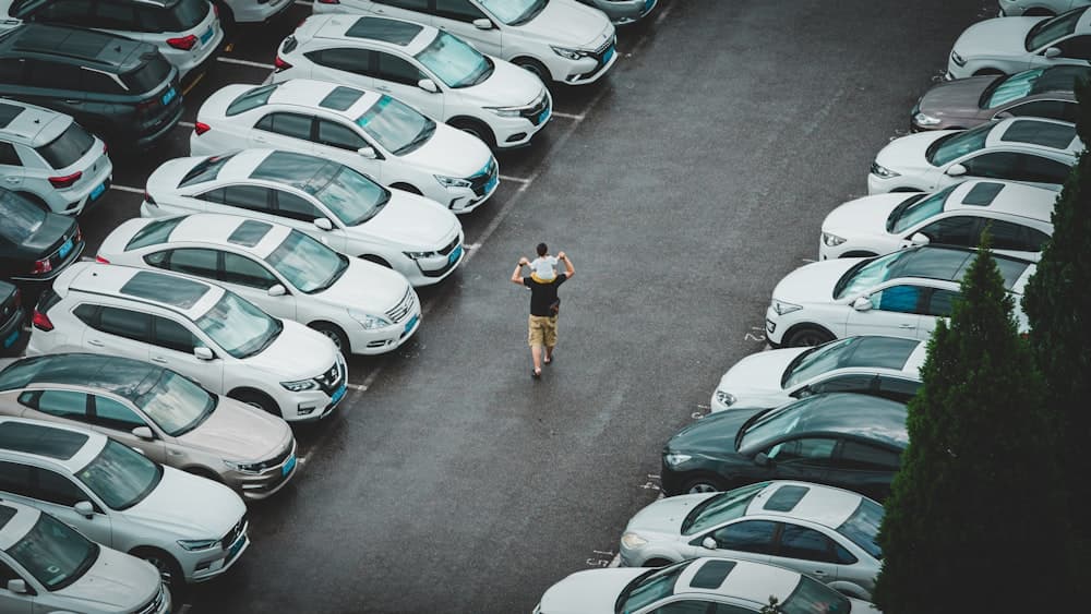 A person walking the aisle of a full car lot