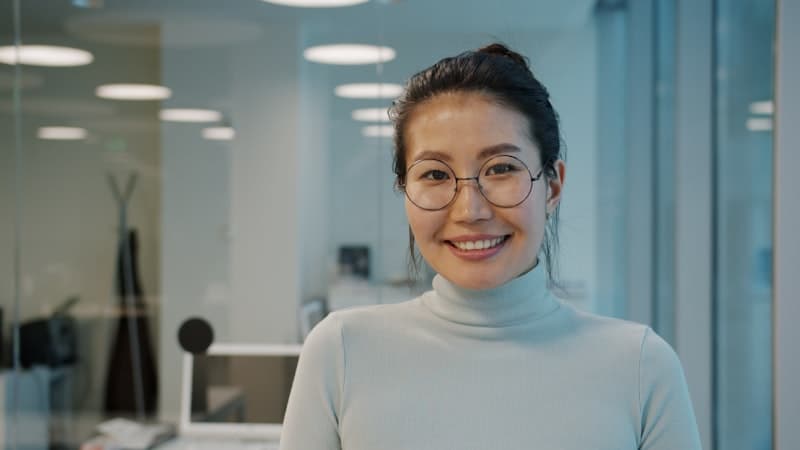 A woman with glasses standing in an office