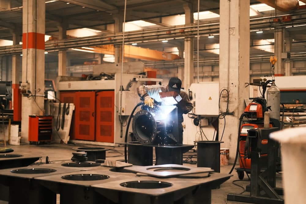A welder working on a part on the factory floor
