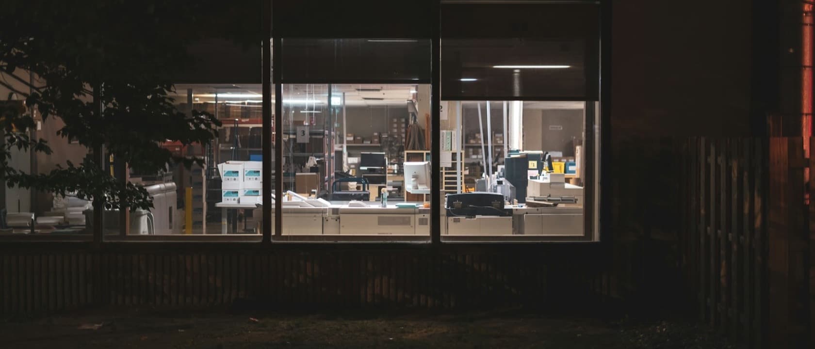 A lit workspace seen through its windows at night