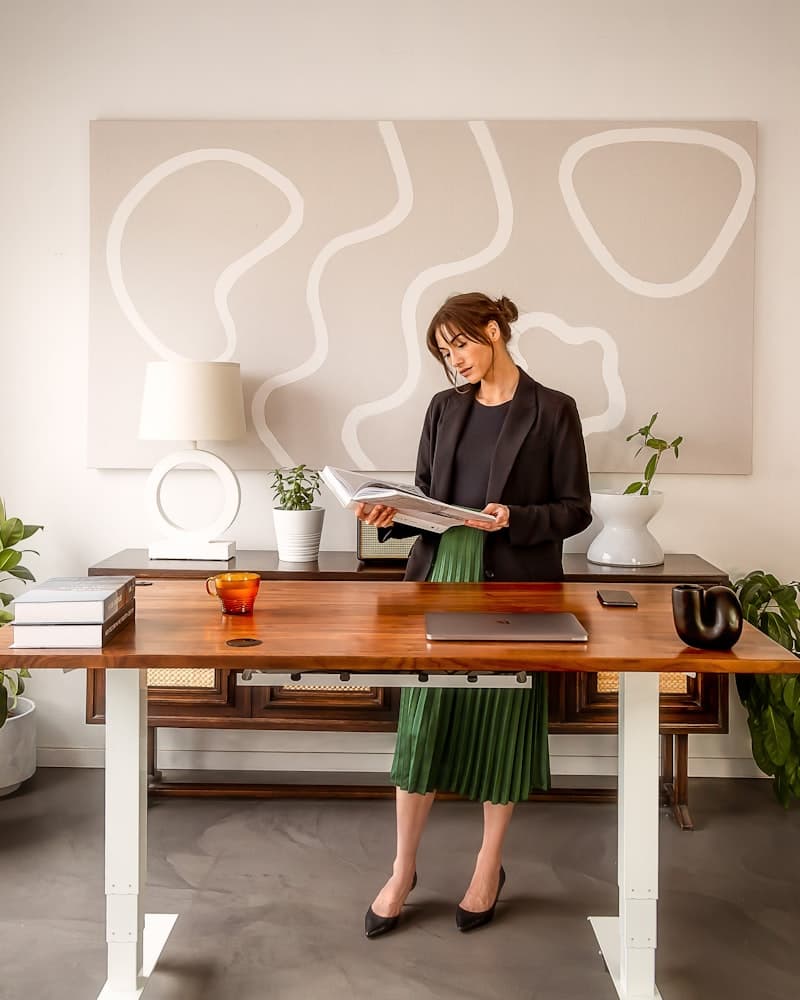A woman standing at an office desk reading a document