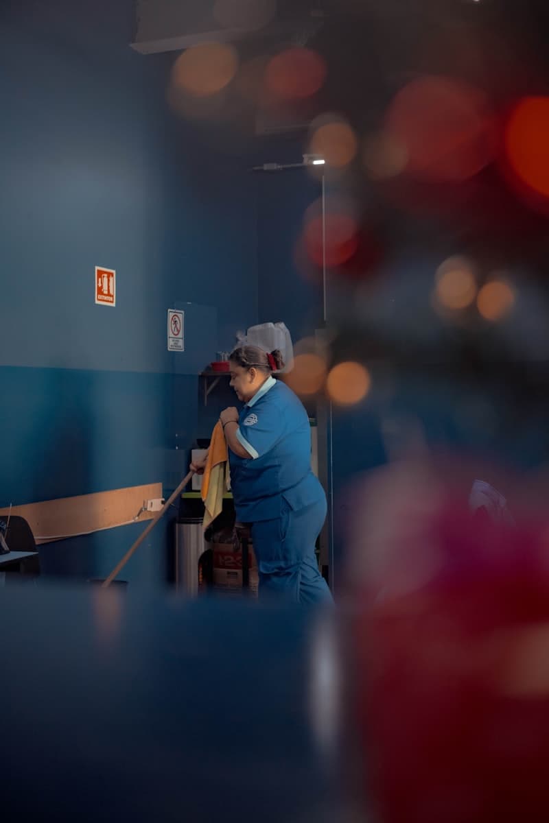 A woman in a blue uniform cleaning a back room