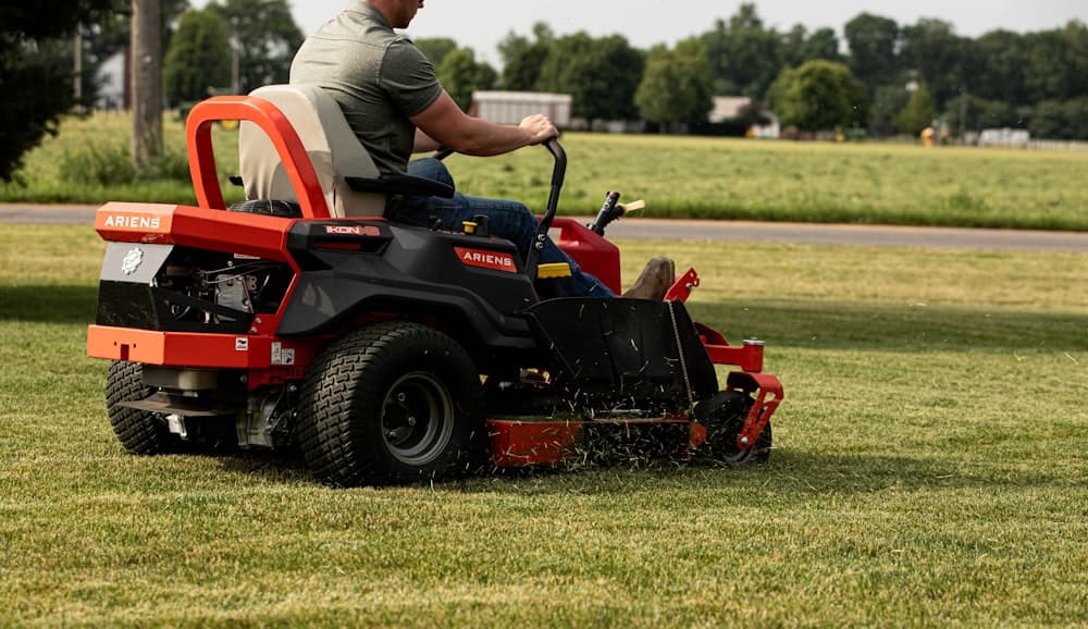 A landscaper cutting grass on a riding mower