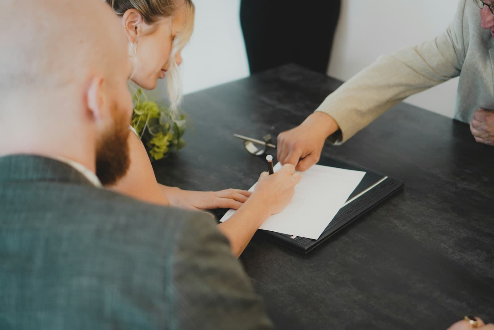 An agent walking clients through paperwork at a dark desk