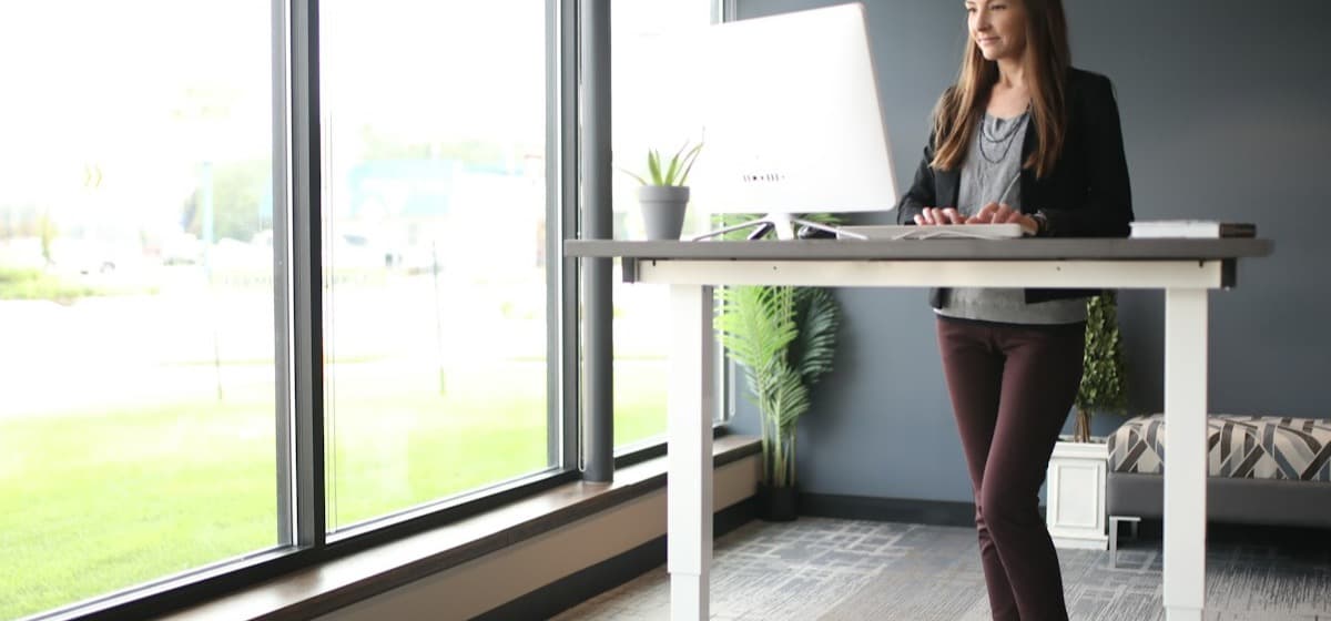 A woman working at a standing desk in a street-front office