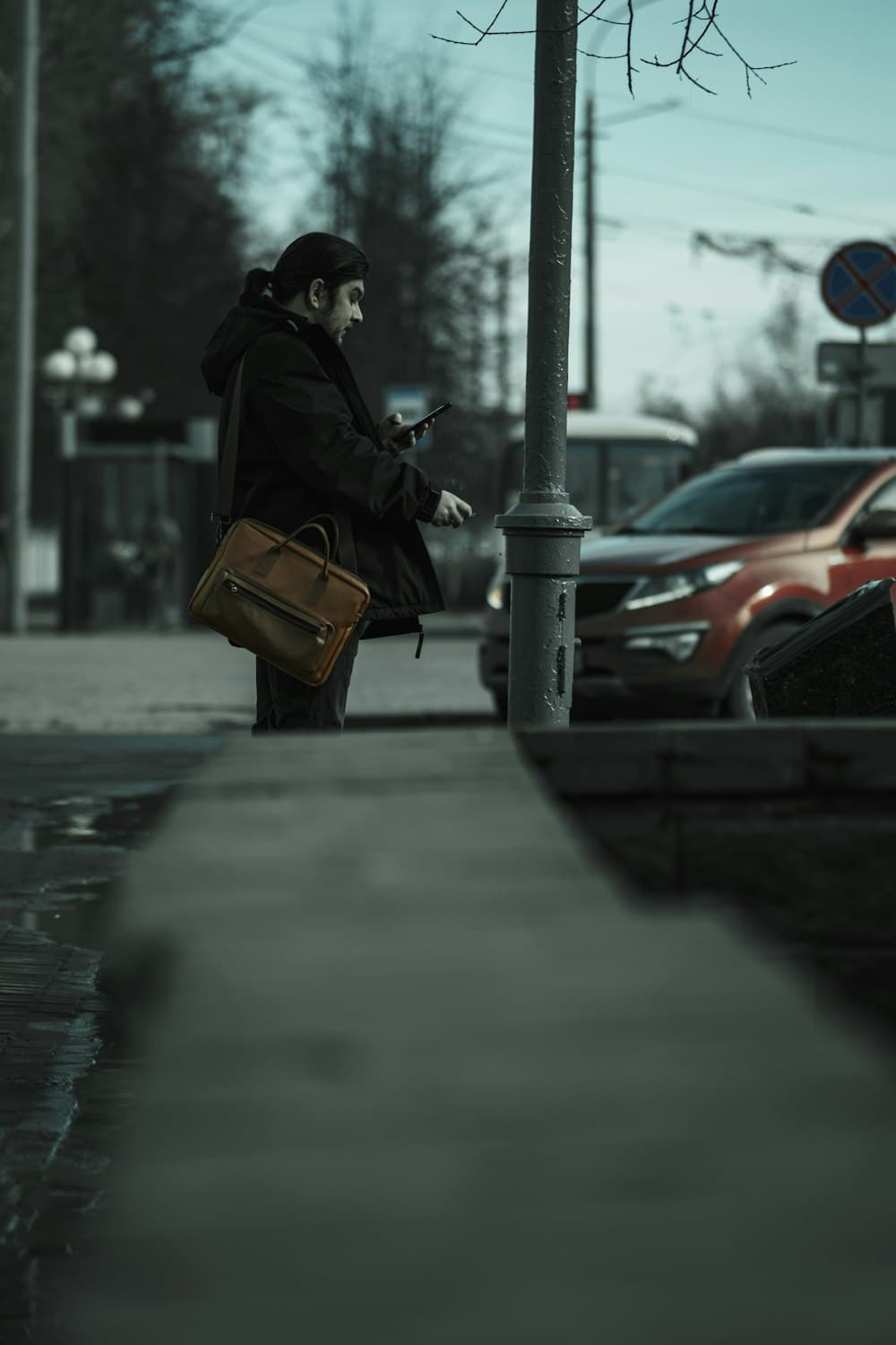 A man with a briefcase checking his phone on the street