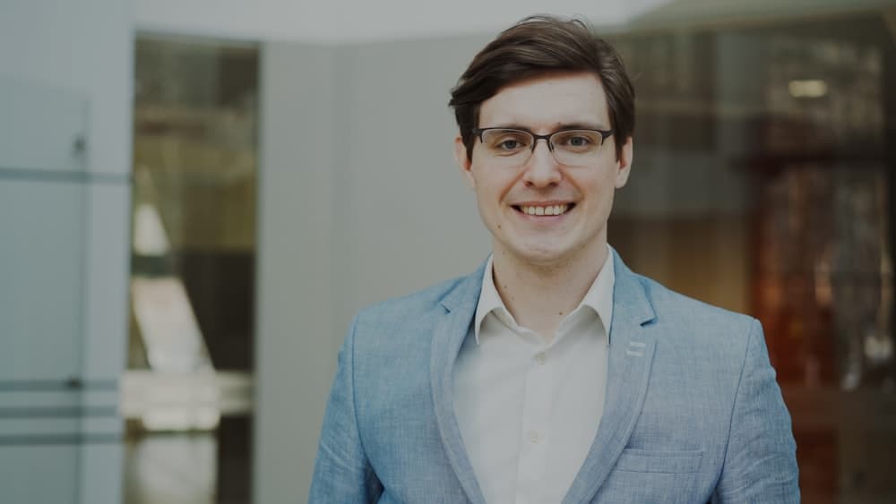 A smiling man in a suit and glasses