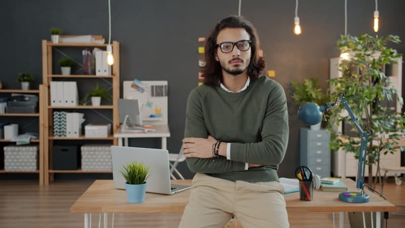 A man with glasses and arms crossed in an office
