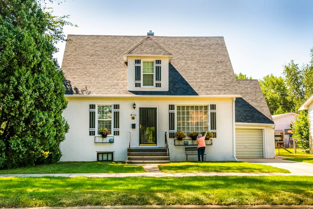 A white house with a trimmed lawn on a residential street