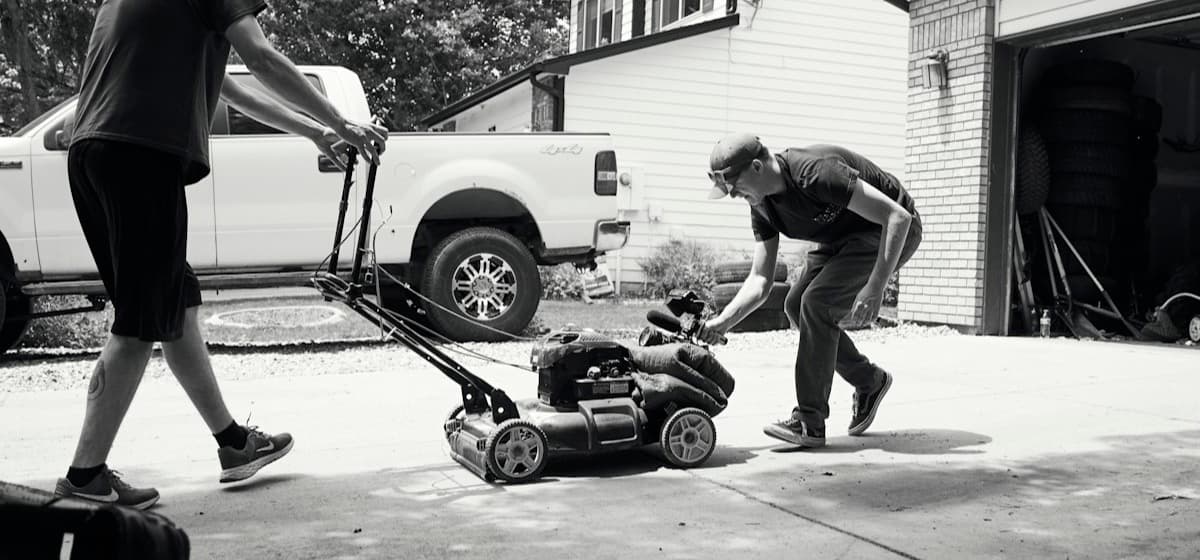 Two crew members loading a mower beside a pickup truck