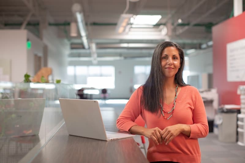 A woman standing at an office desk with a laptop