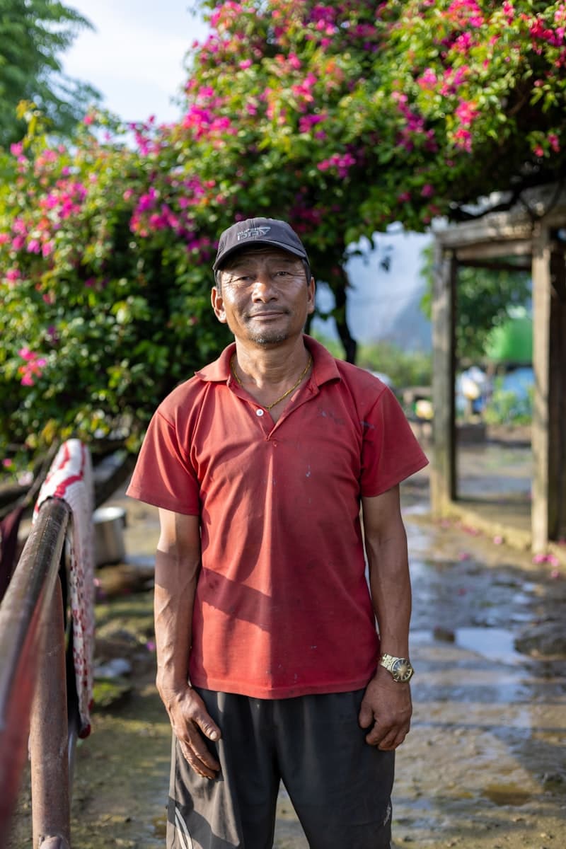 A man in a red shirt and cap standing outdoors