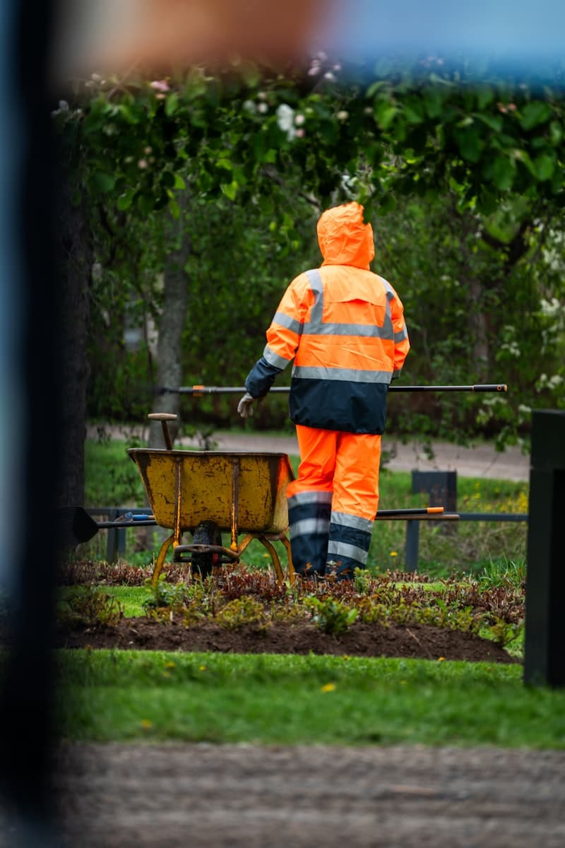A worker in orange gear tending a garden bed
