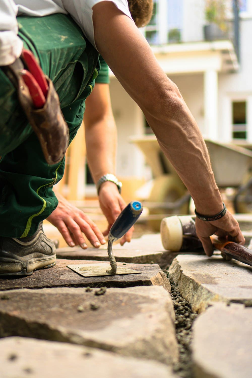 A worker setting pavers on a patio in progress