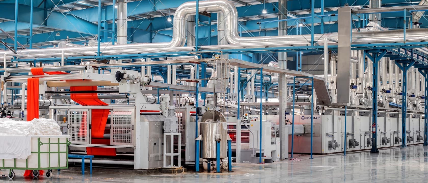 An industrial hall with machinery and overhead pipes