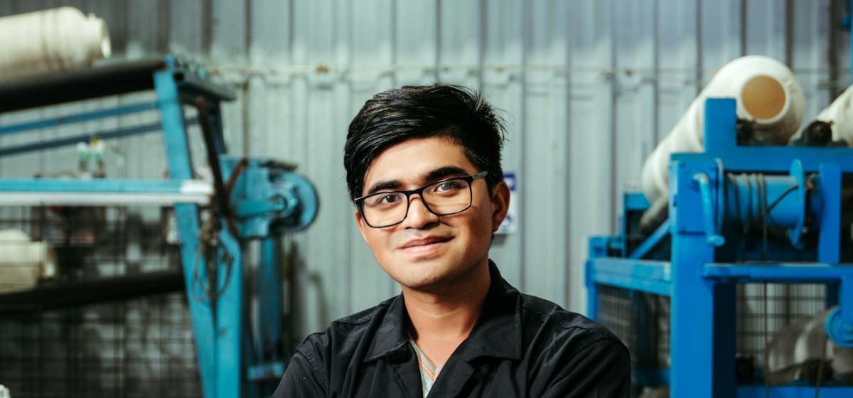 A man standing on a factory floor with his arms crossed