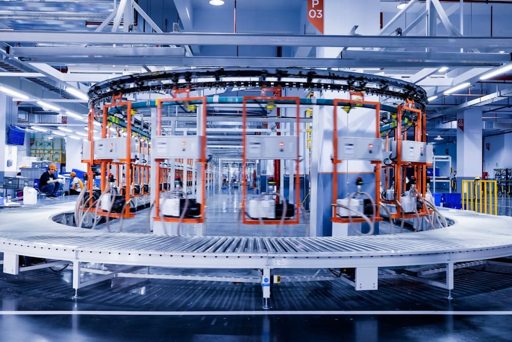 A large machine on a production floor with people working around it