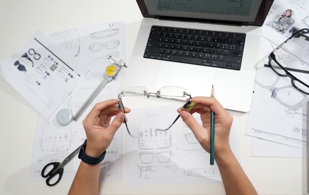 Hands holding glasses over design drawings on a desk