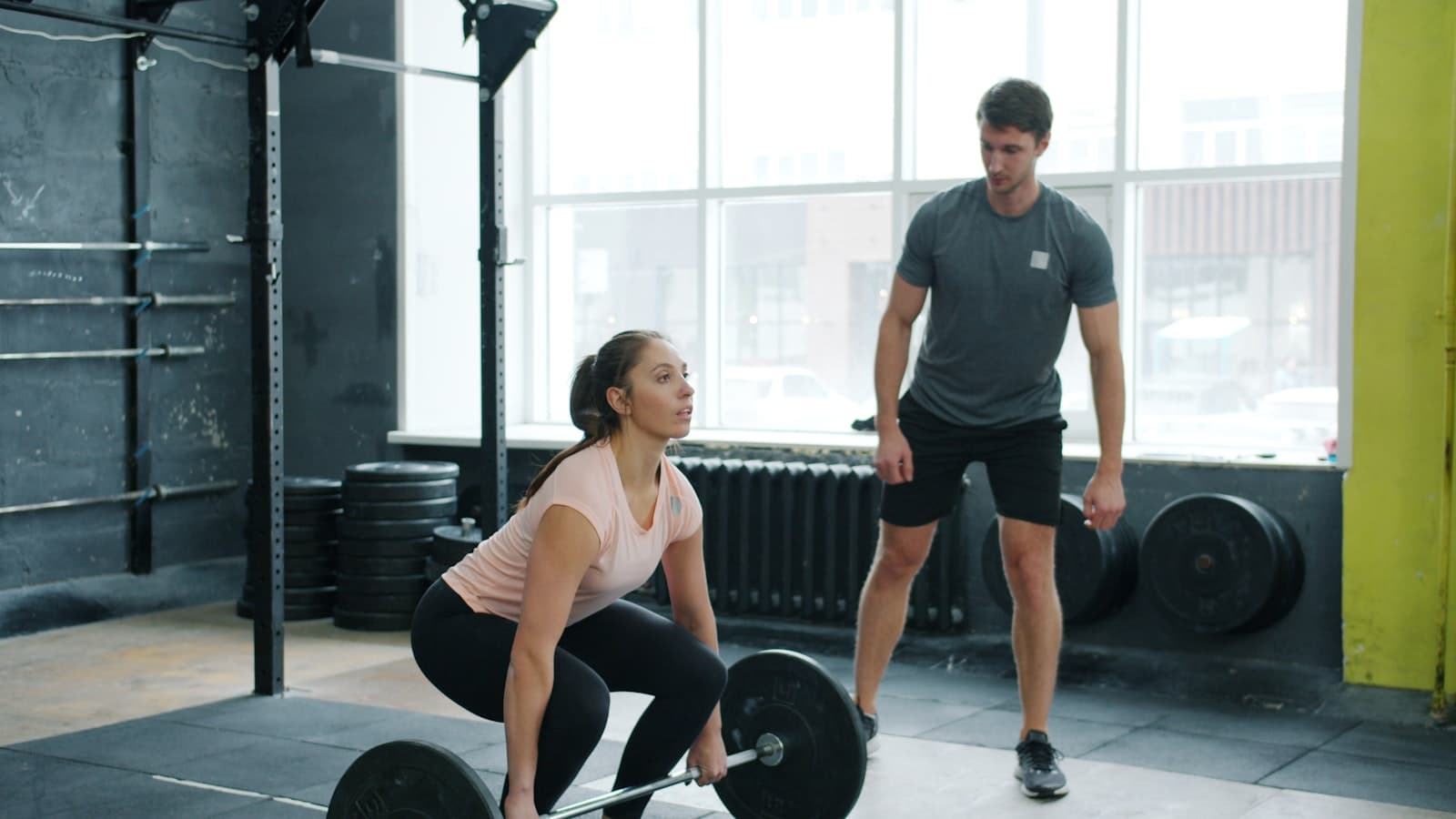 A trainer spotting a client lifting weights in a gym