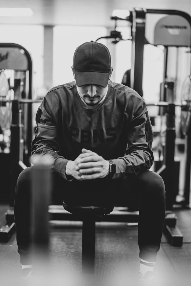 A trainer in a knit cap sitting on a gym bench