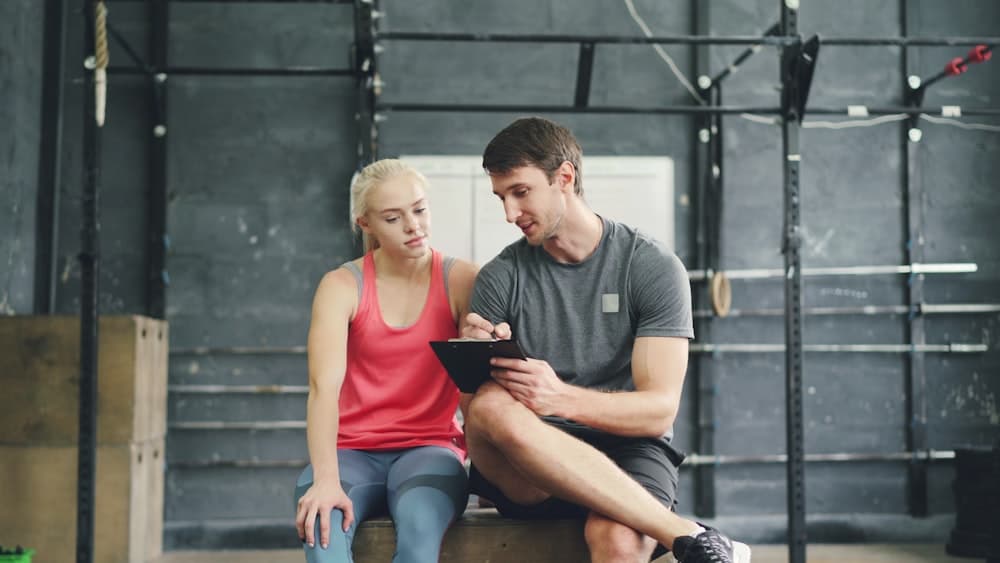 A trainer reviewing progress with a client on a tablet