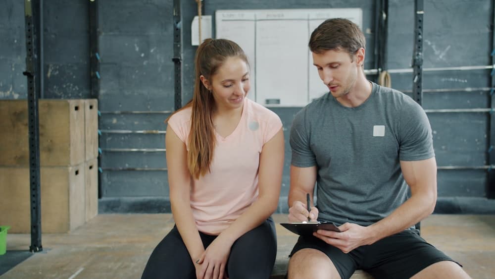 A trainer and client going over a plan on a tablet