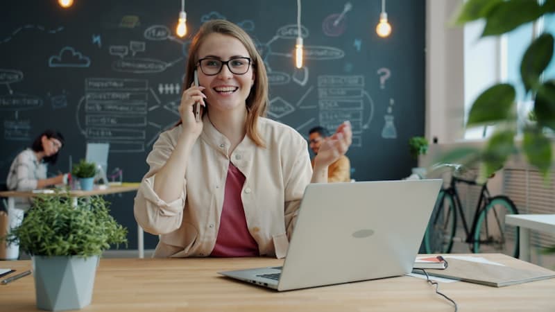 A woman on the phone at a desk with a laptop