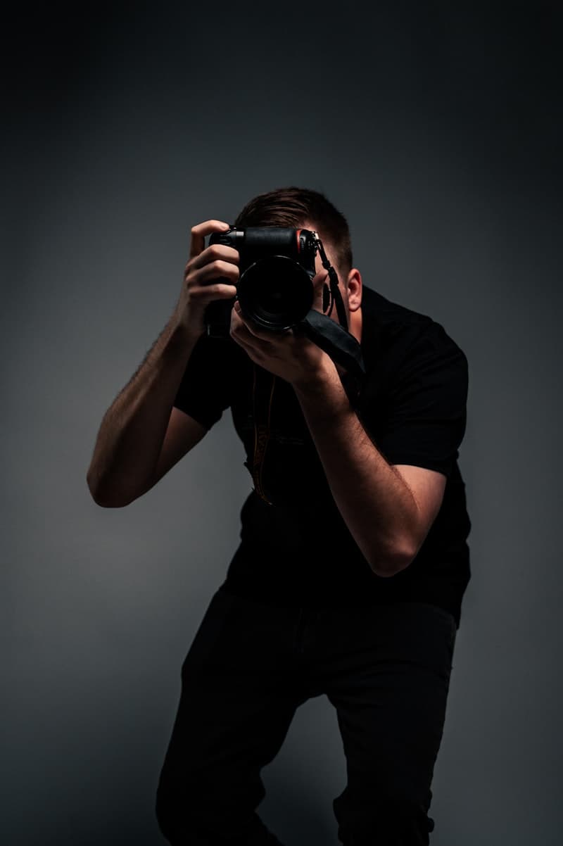 A man in a black t-shirt holding a DSLR camera