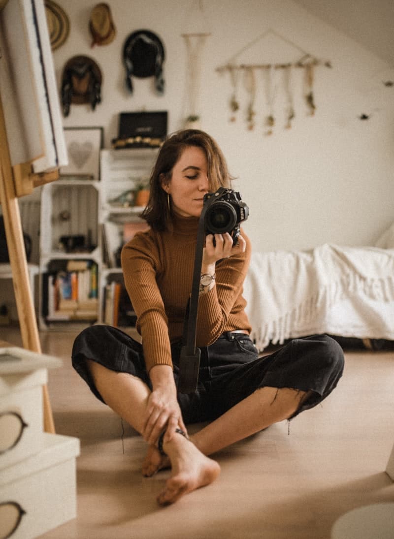 A woman seated on a wooden floor with her camera