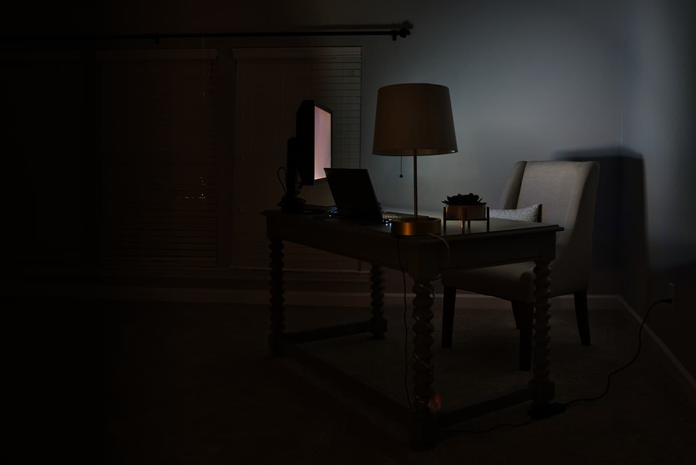A desk lamp and laptop lit for evening work