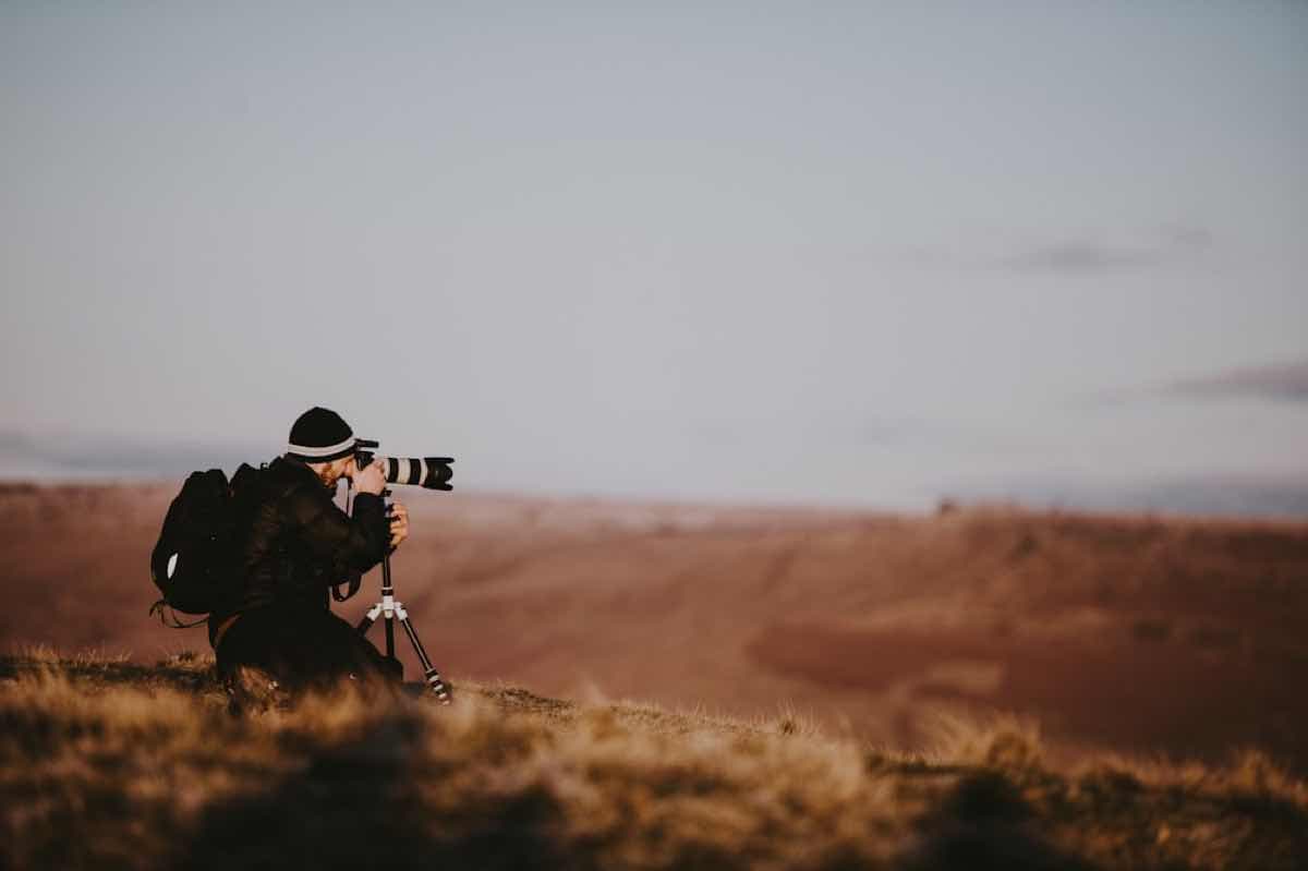 A photographer shooting from a hillside at golden hour