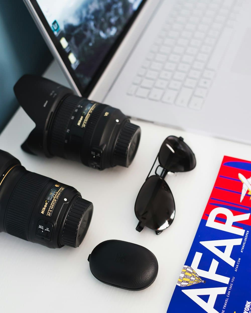 Camera lenses and a laptop laid out on a work desk