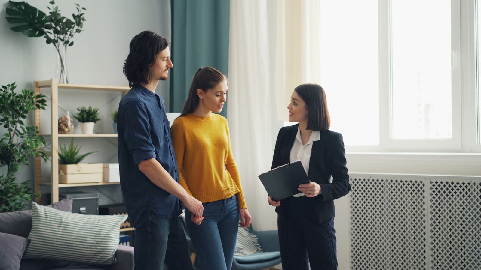 An agent with a clipboard walking a couple through a living room