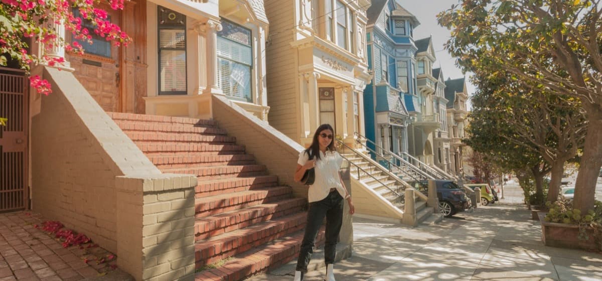 An agent with a shoulder bag walking a street of row houses
