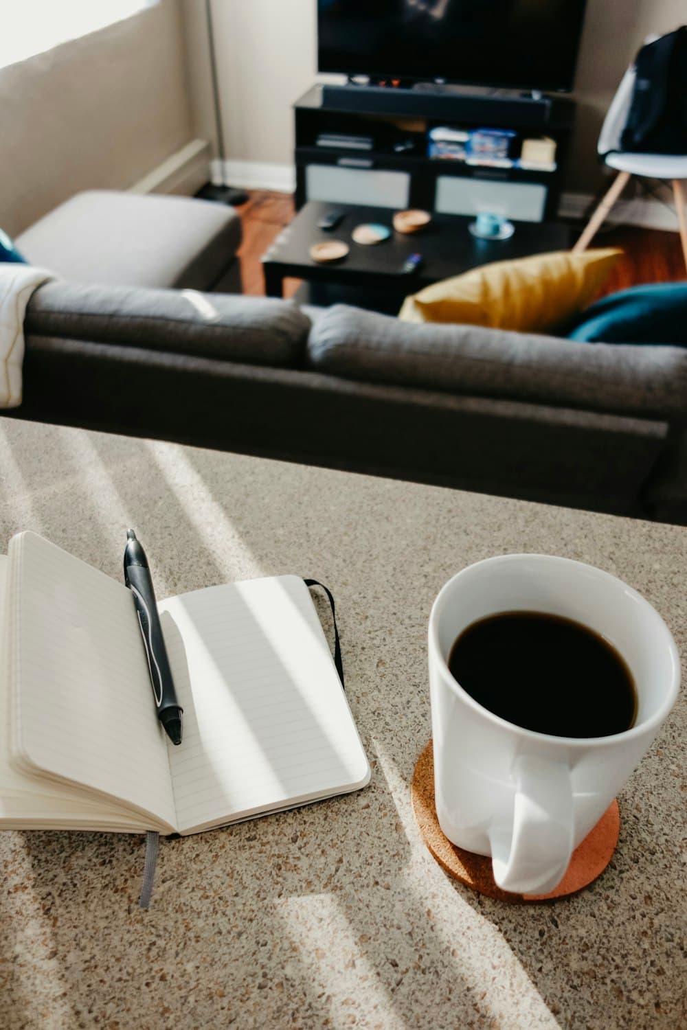 Coffee and a pen on an open notebook at first light