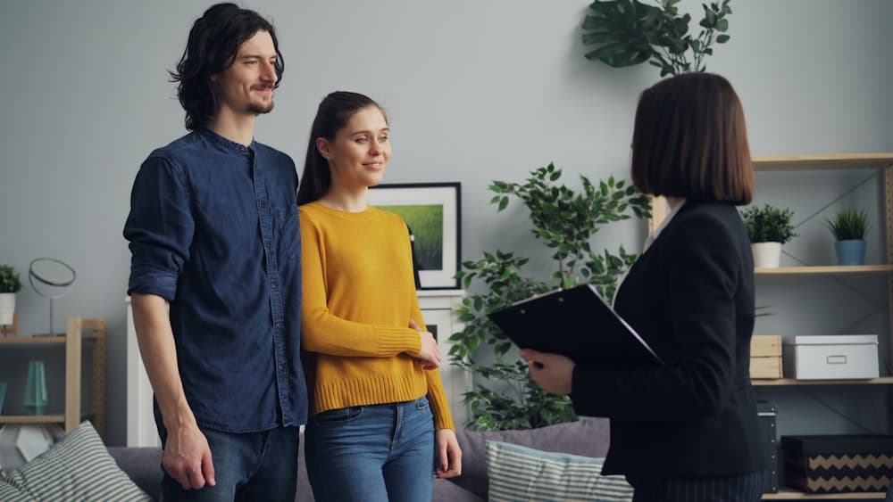 Two people being shown through a bright living room