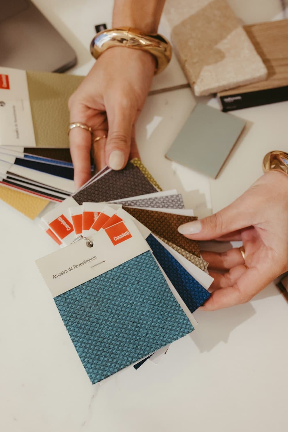 Hands choosing fabric samples from a design palette