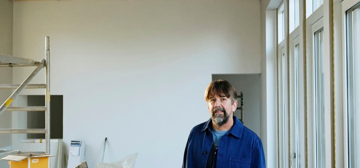 A contractor standing in a room mid-renovation, plans in hand
