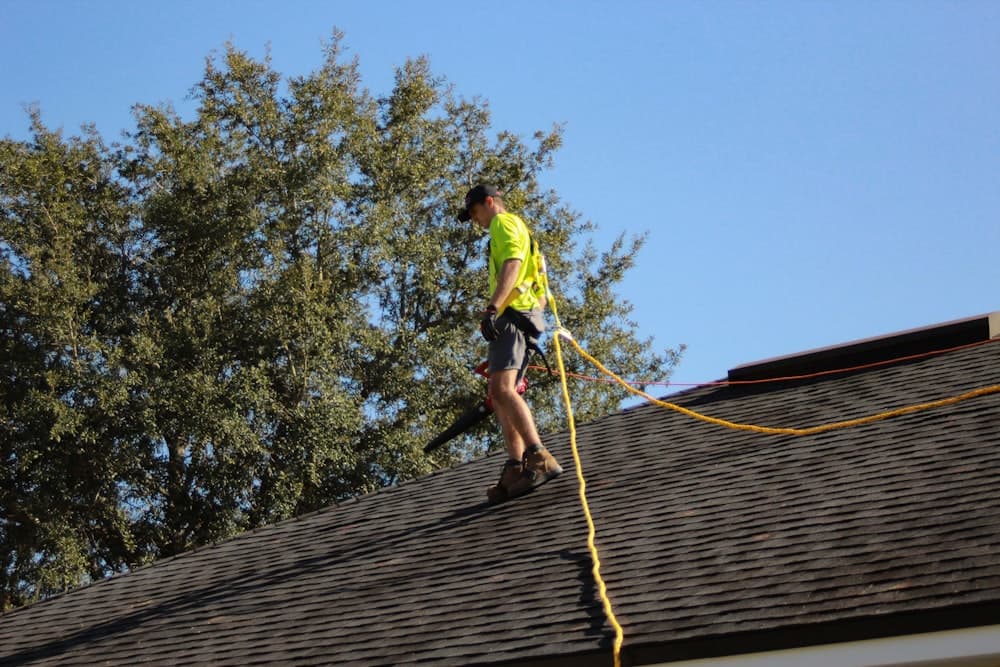 A roofer working on a ridge with a safety rope