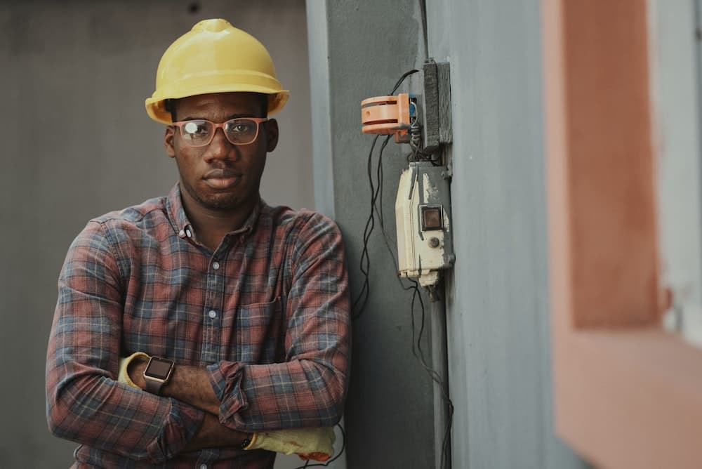 A man in a plaid shirt and yellow hard hat at a job site