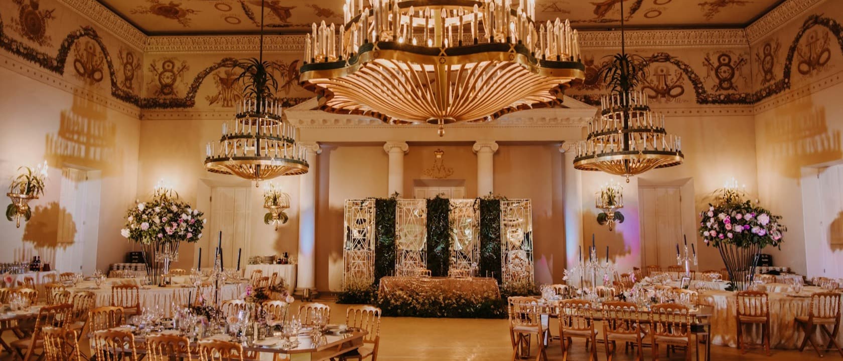 A banquet hall with chandeliers and tables set for an event