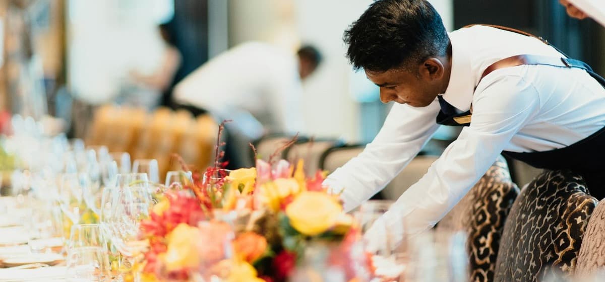 A staff member leaning in to finish a long table setting