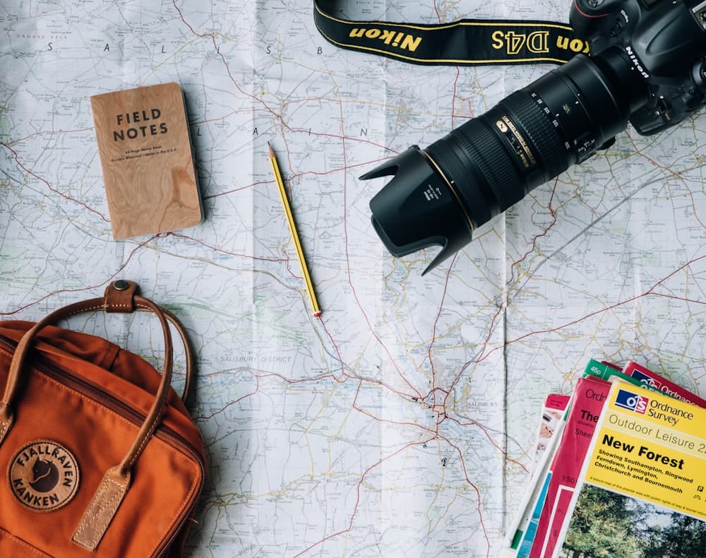 A camera, notebook, and bag laid out for a trip