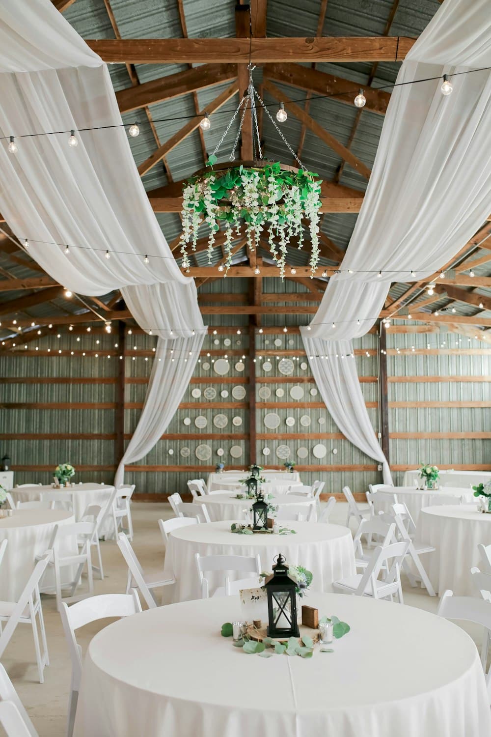 A draped barn reception hall set with round tables