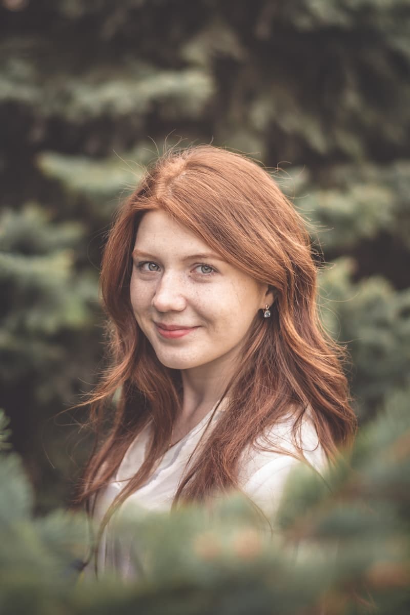 A woman with red hair among evergreens